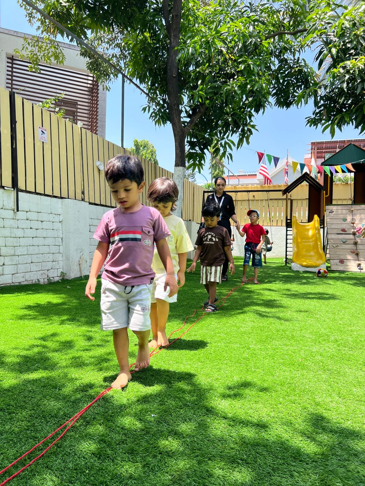 Children walking a balance rope on the lawn