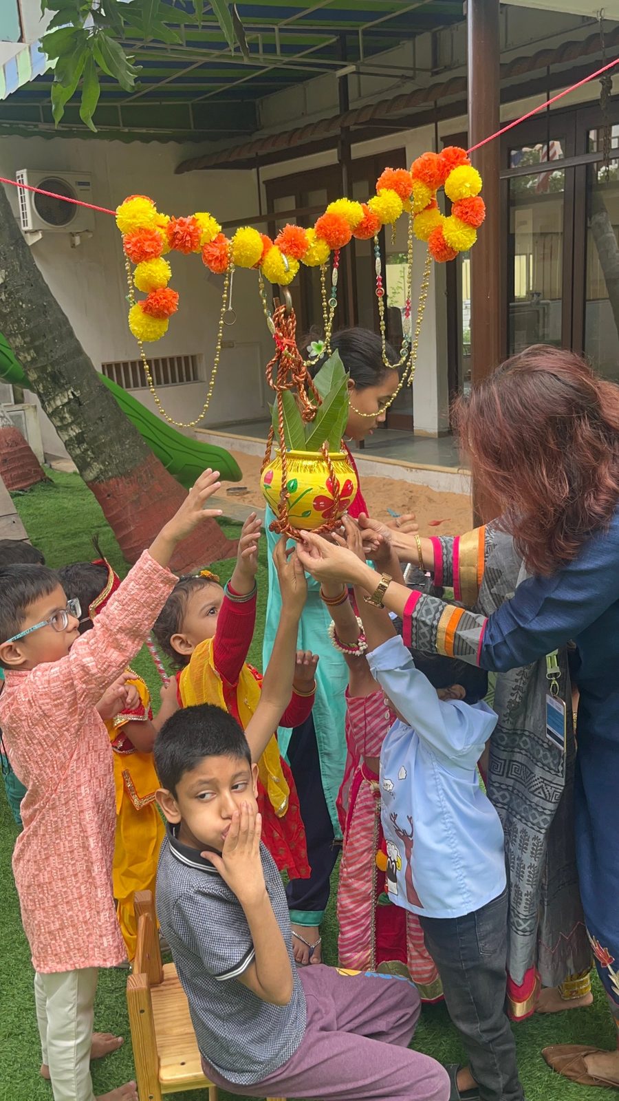 Children celebrating a festival with a decorated pot